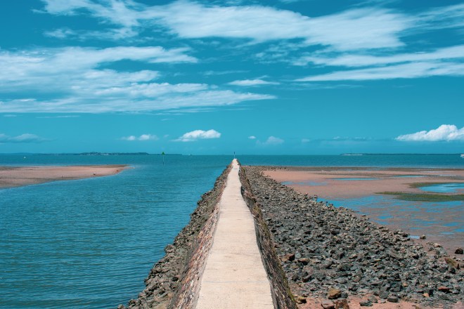 beach breakwater blue sky clouds